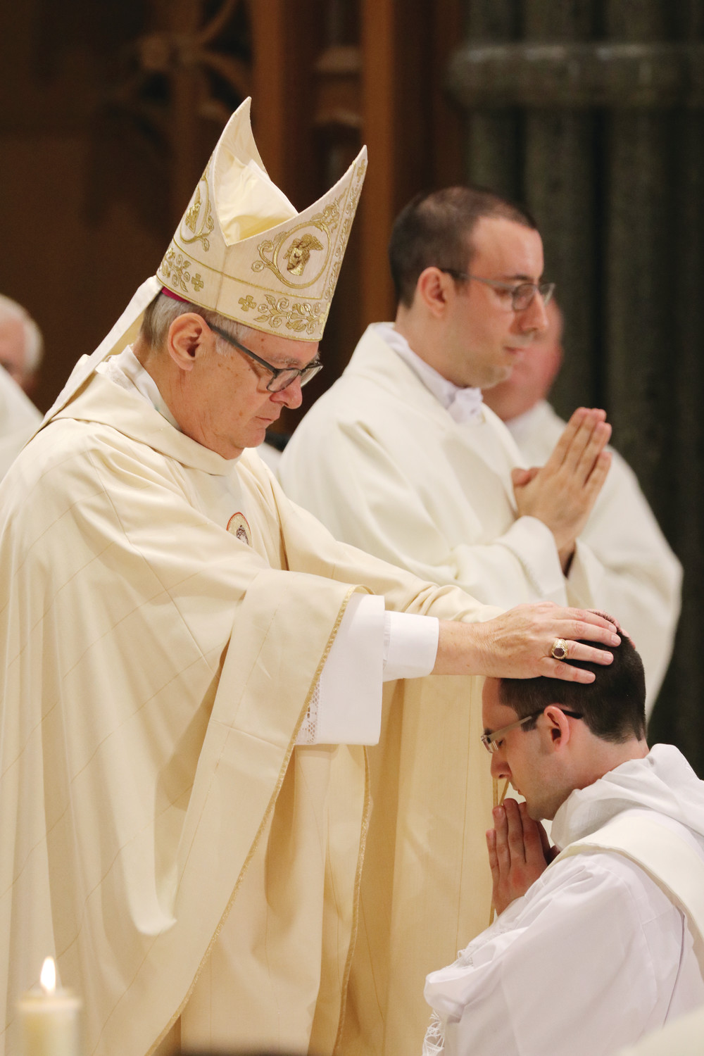Bishop Thomas J. Tobin lays his hands upon the head of the elect, marking the moment that Father Phillip Dufour is welcomed into the priesthood.